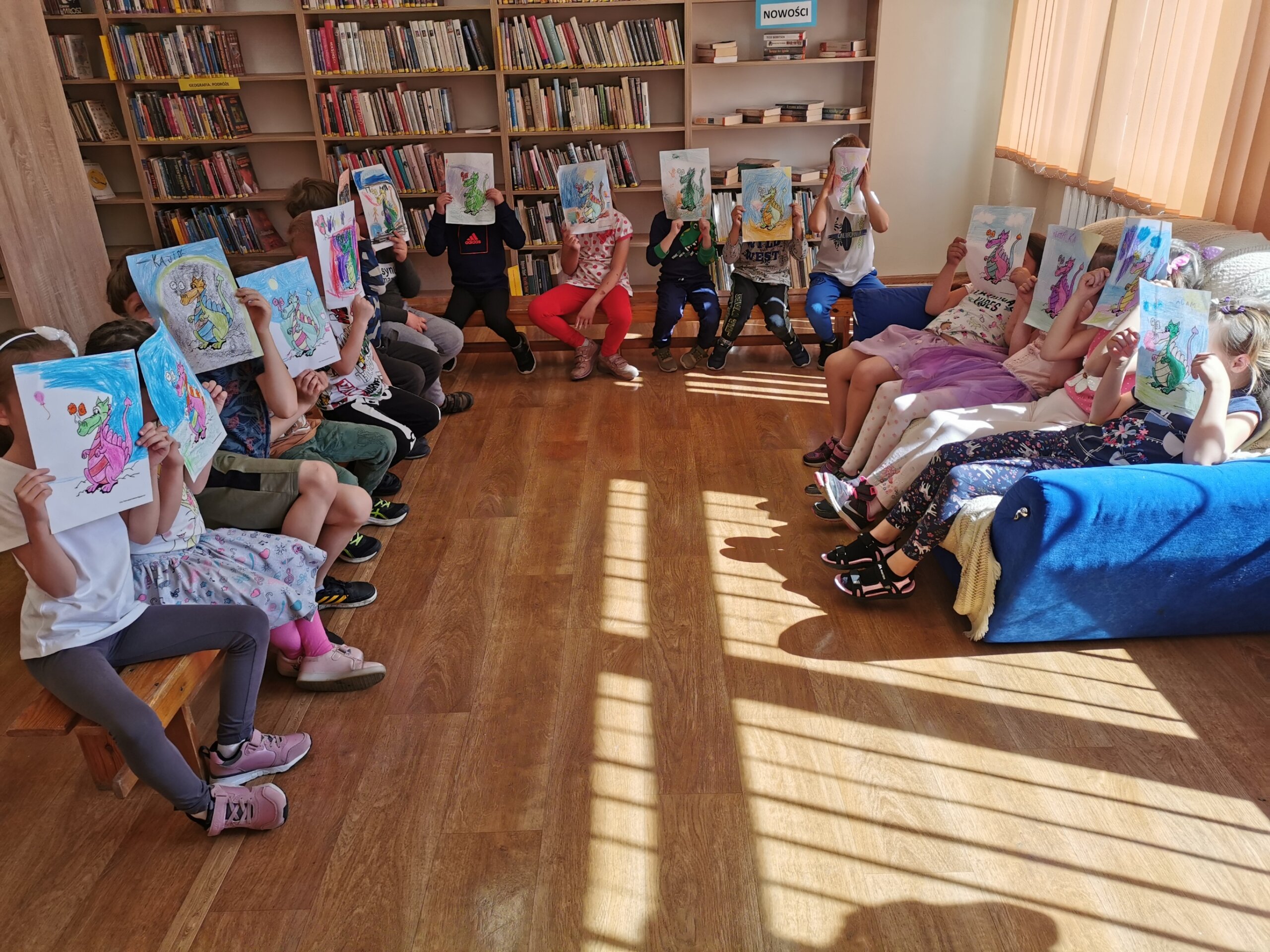 Dzieci w bibliotece pokazują swoje rysunki