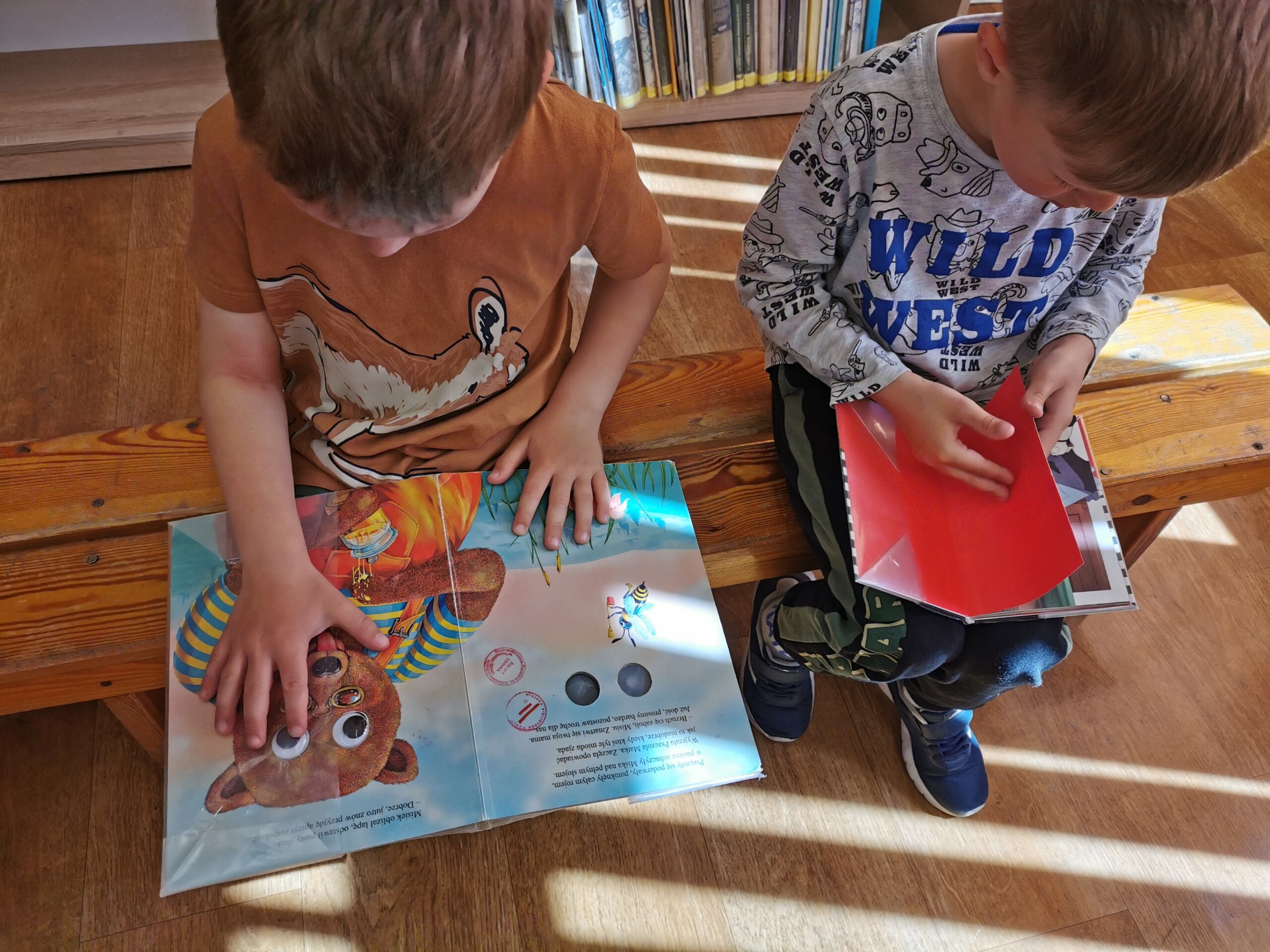 Dzieci w bibliotece przeglądają książki
