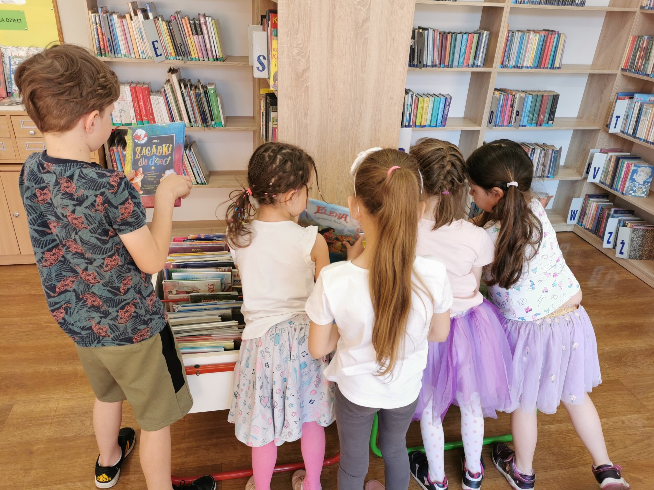 Dzieci w bibliotece przeglądaja książki