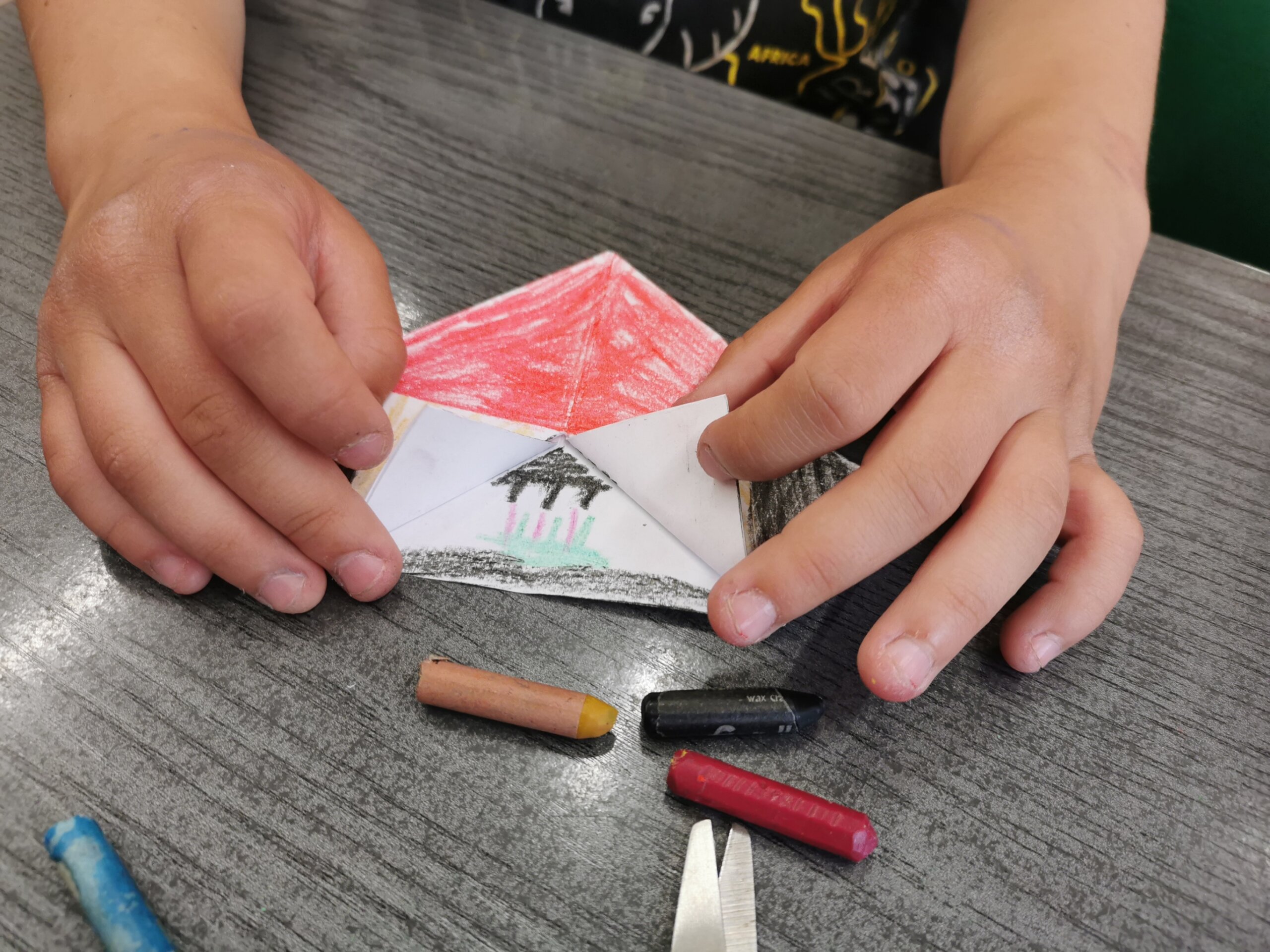 Dziecko pokazuje wykonany z papieru techniką origami namiot