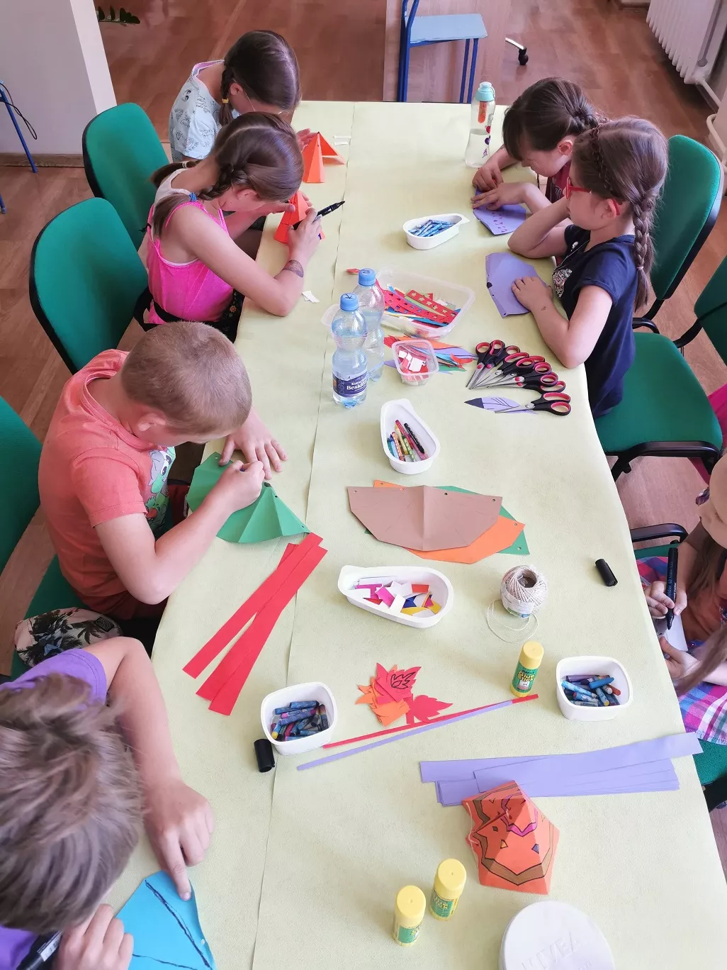 Dzieci wykonujące prace plastyczne przy stole