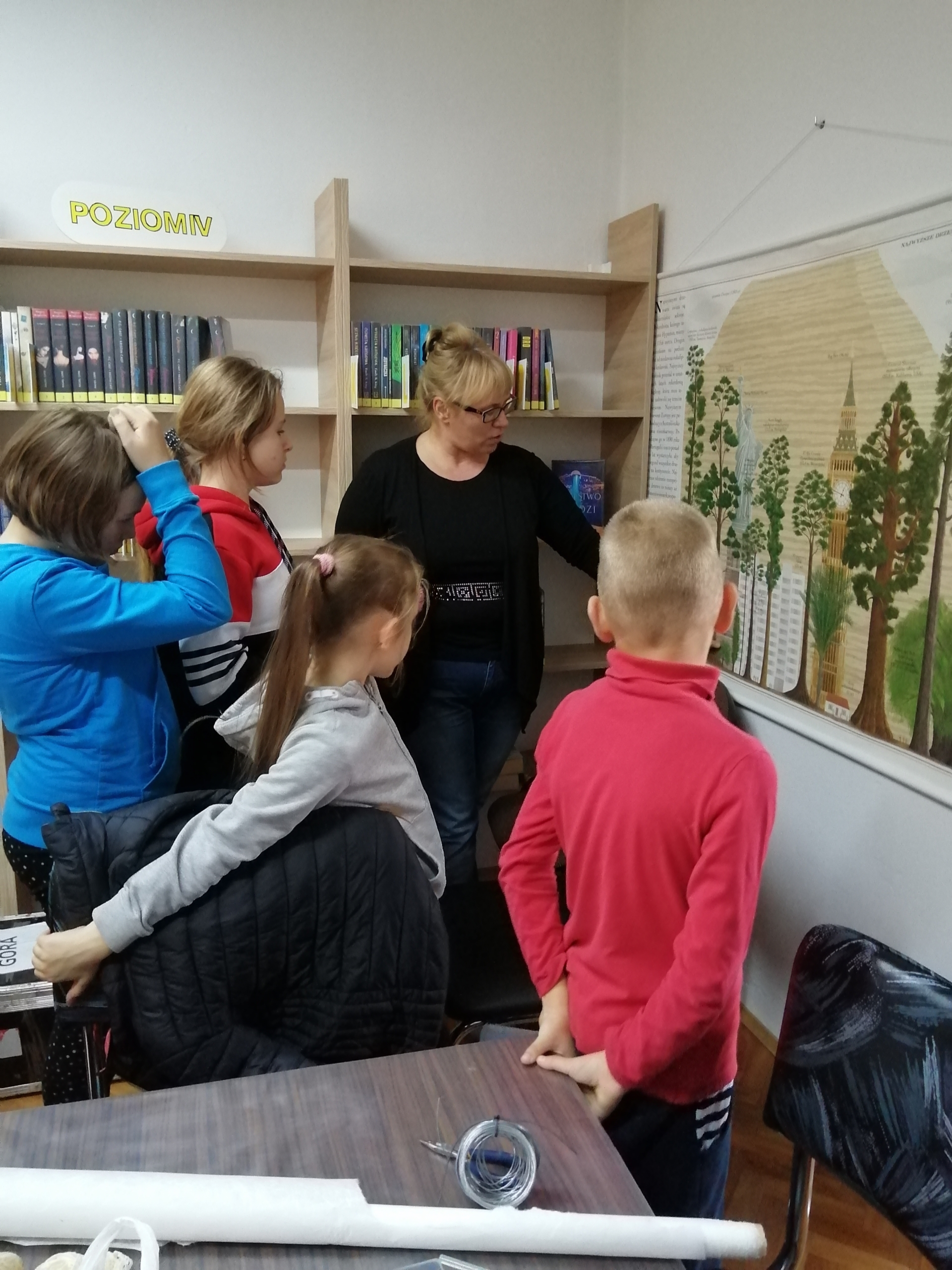  Bibliotekarka pokazująca dzieciom planszę z drzewami