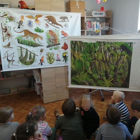 Dzieci oglądające plansze z drzewami i zwierzętami