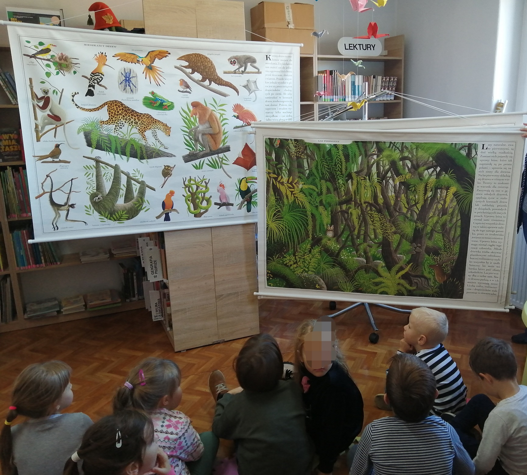Dzieci oglądające plansze z drzewami i zwierzętami