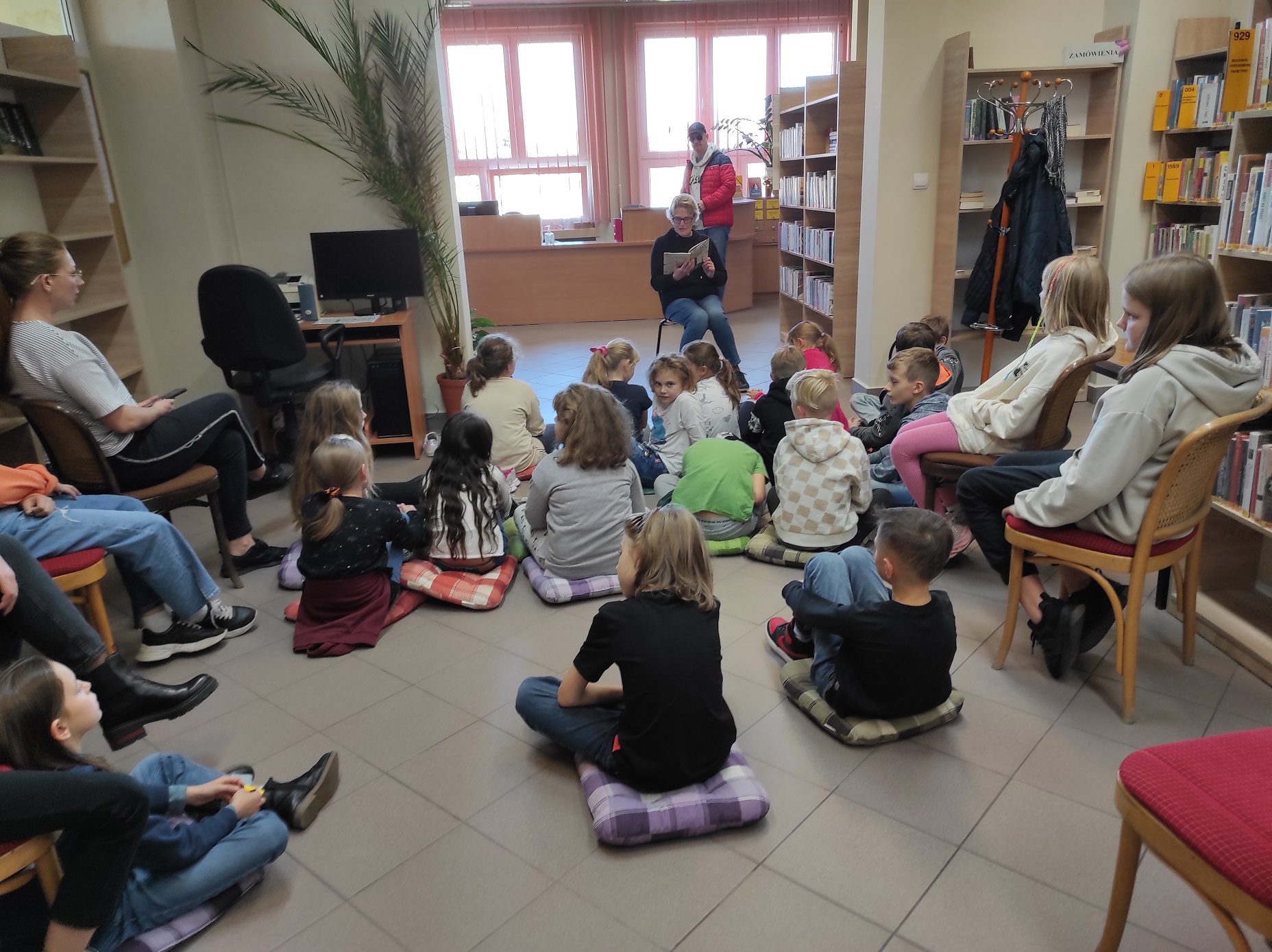 Dzieci słuchające czytającej bibliotekarki