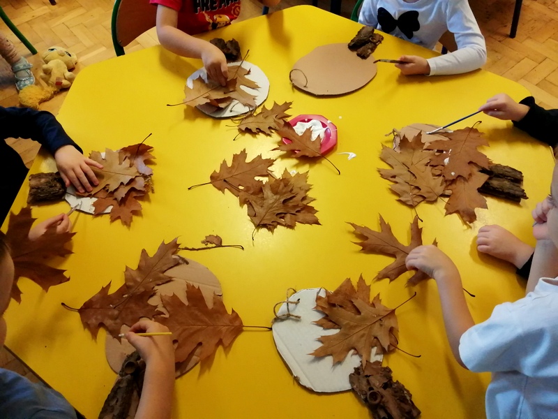 Dzieci wykonują drzewka z suchych liści