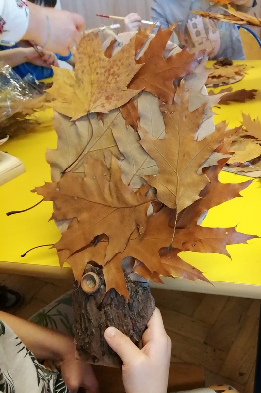Dziecko prezentuje wykonane drzewko z liści 