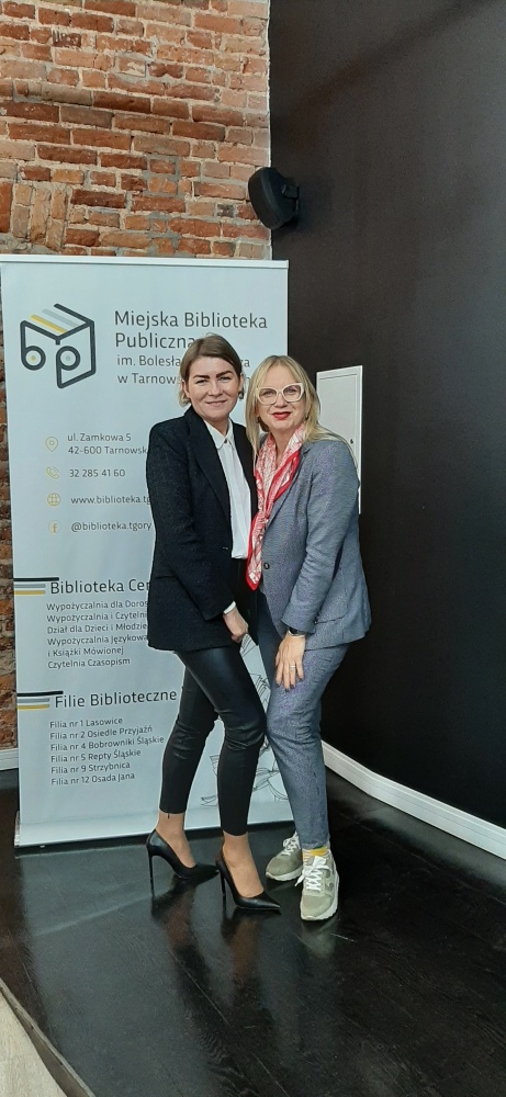 Marzena Rogalska z dyrektor biblioteki stojące na tle reklamy