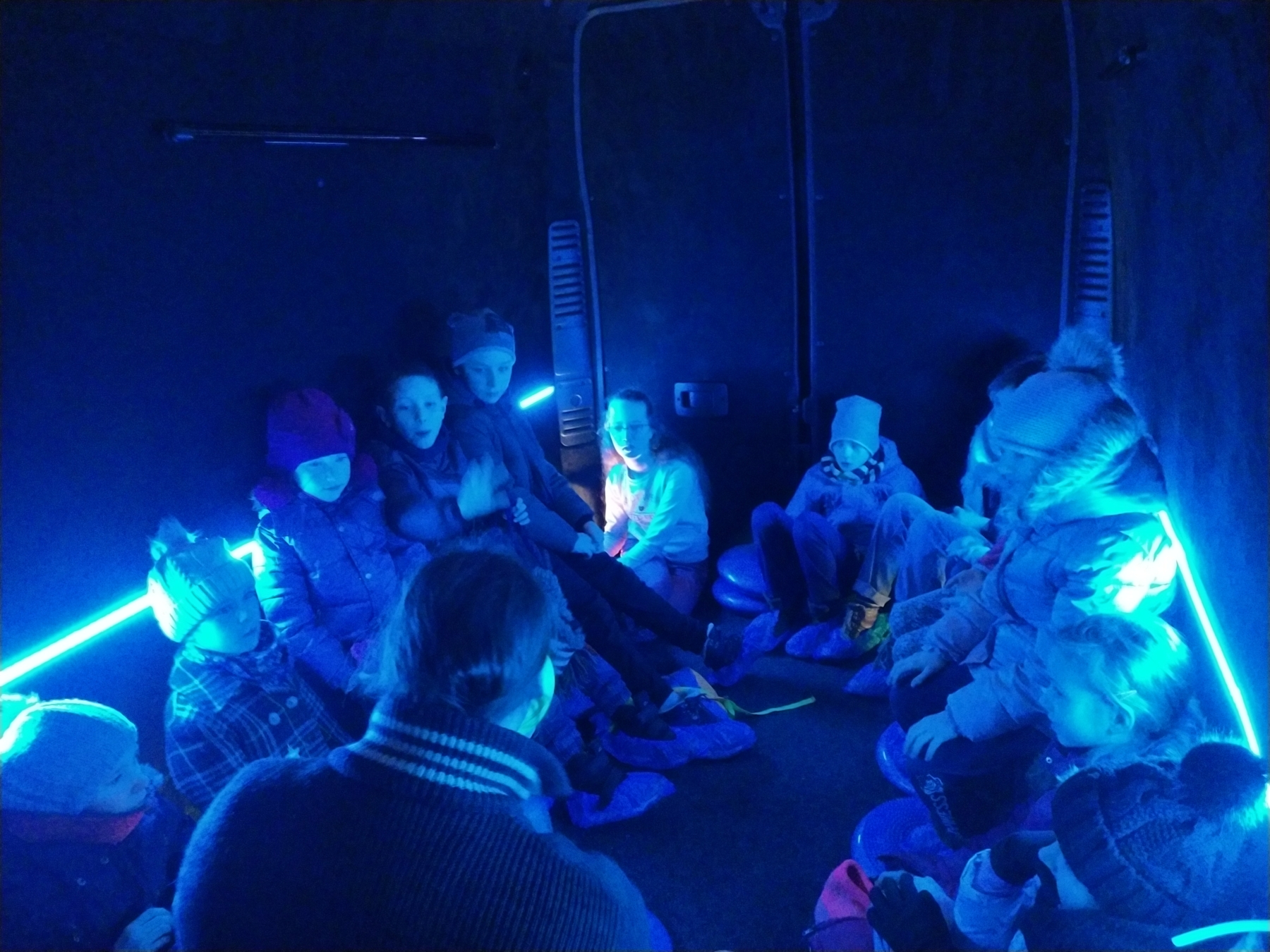 Dzieci siedzące w busie oświetlone niebieskim światłem