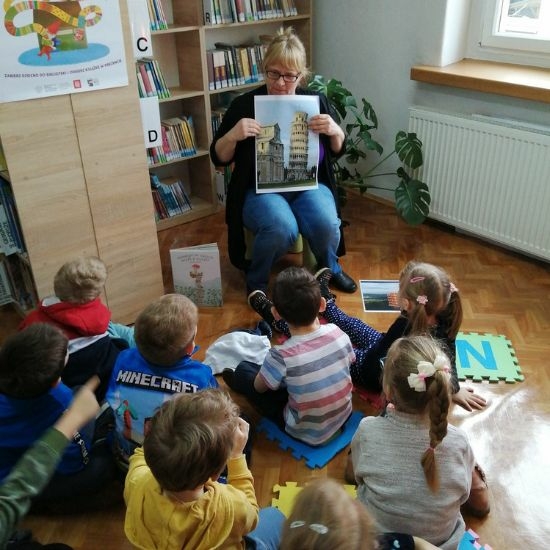 Bibliotekarka pokazuje dzieciom książkę.