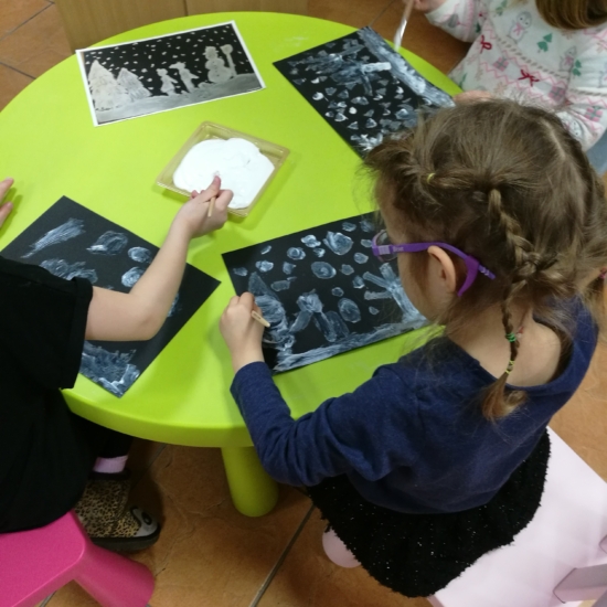 Dzieci przy stoliku malują zimowy pejzaż