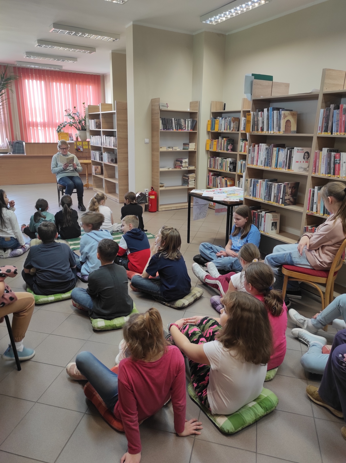 Dzieci słuchające czytającej bibliotekarki