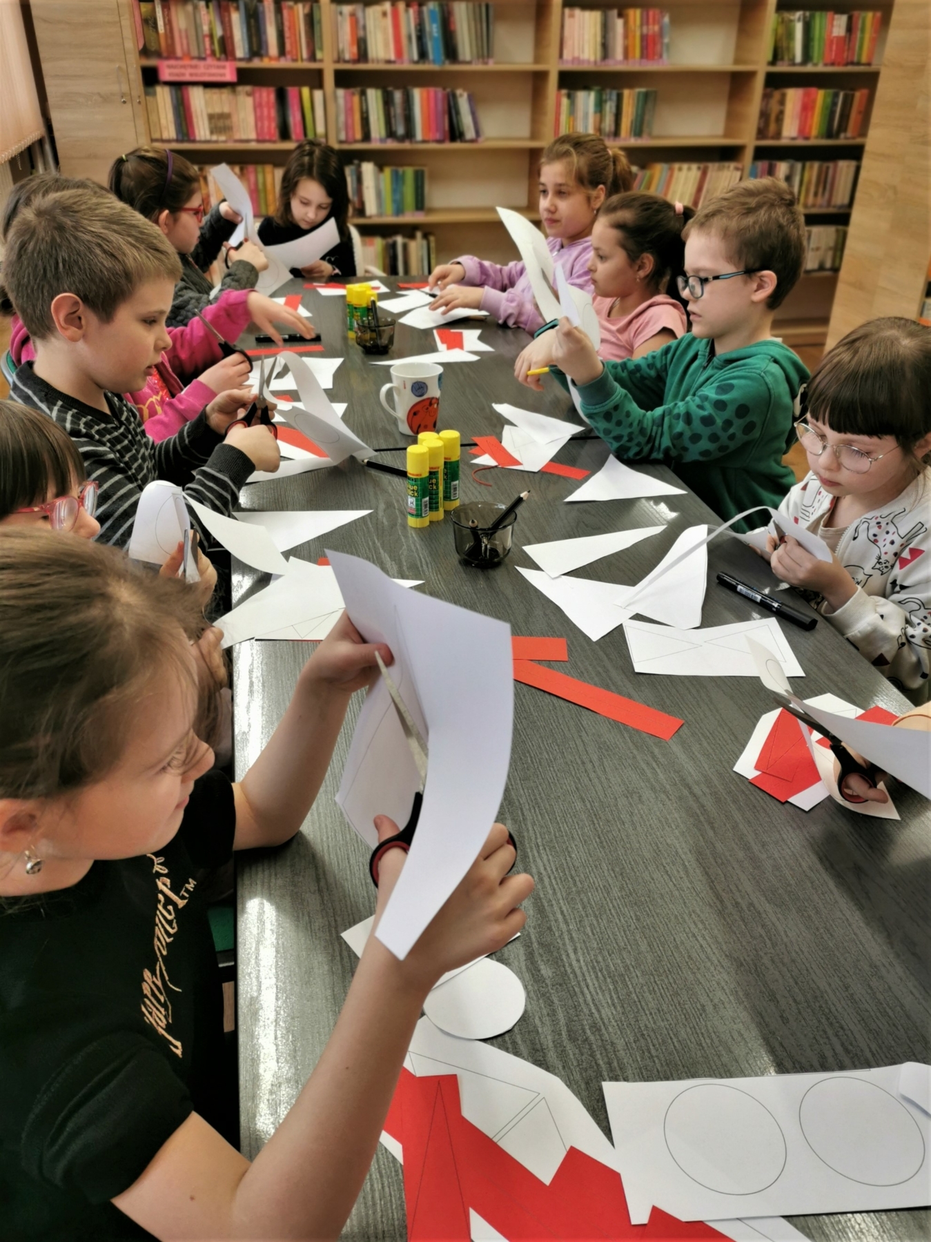 Dzieci wycinające papierowe bociany