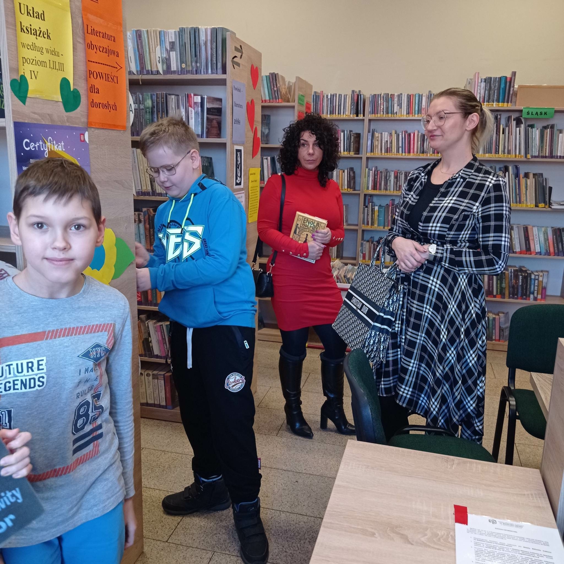 Dzieci i ich opiekunki oglądające bibliotekę