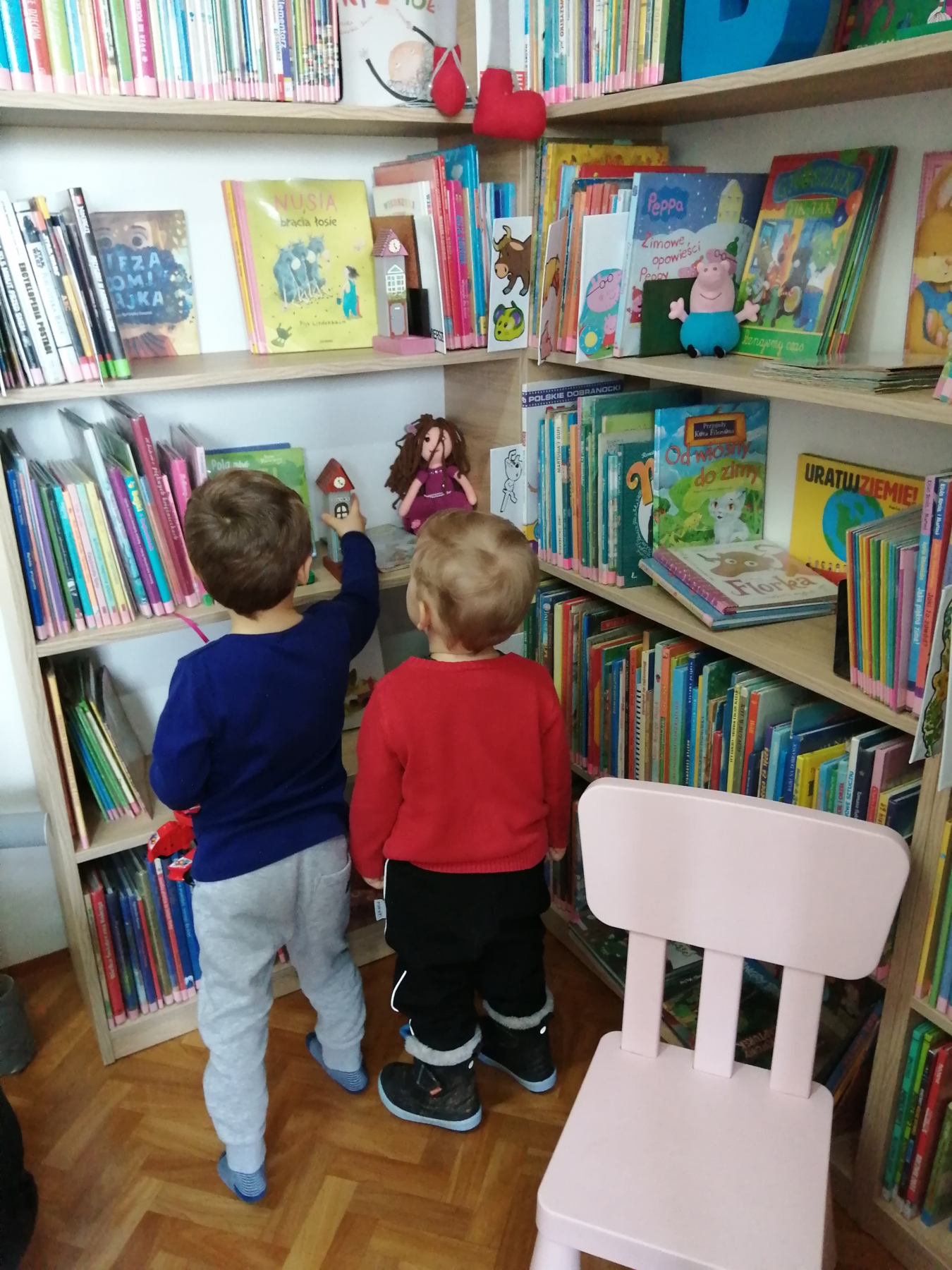 Dzieci oglądają książki na półkach w bibliotece