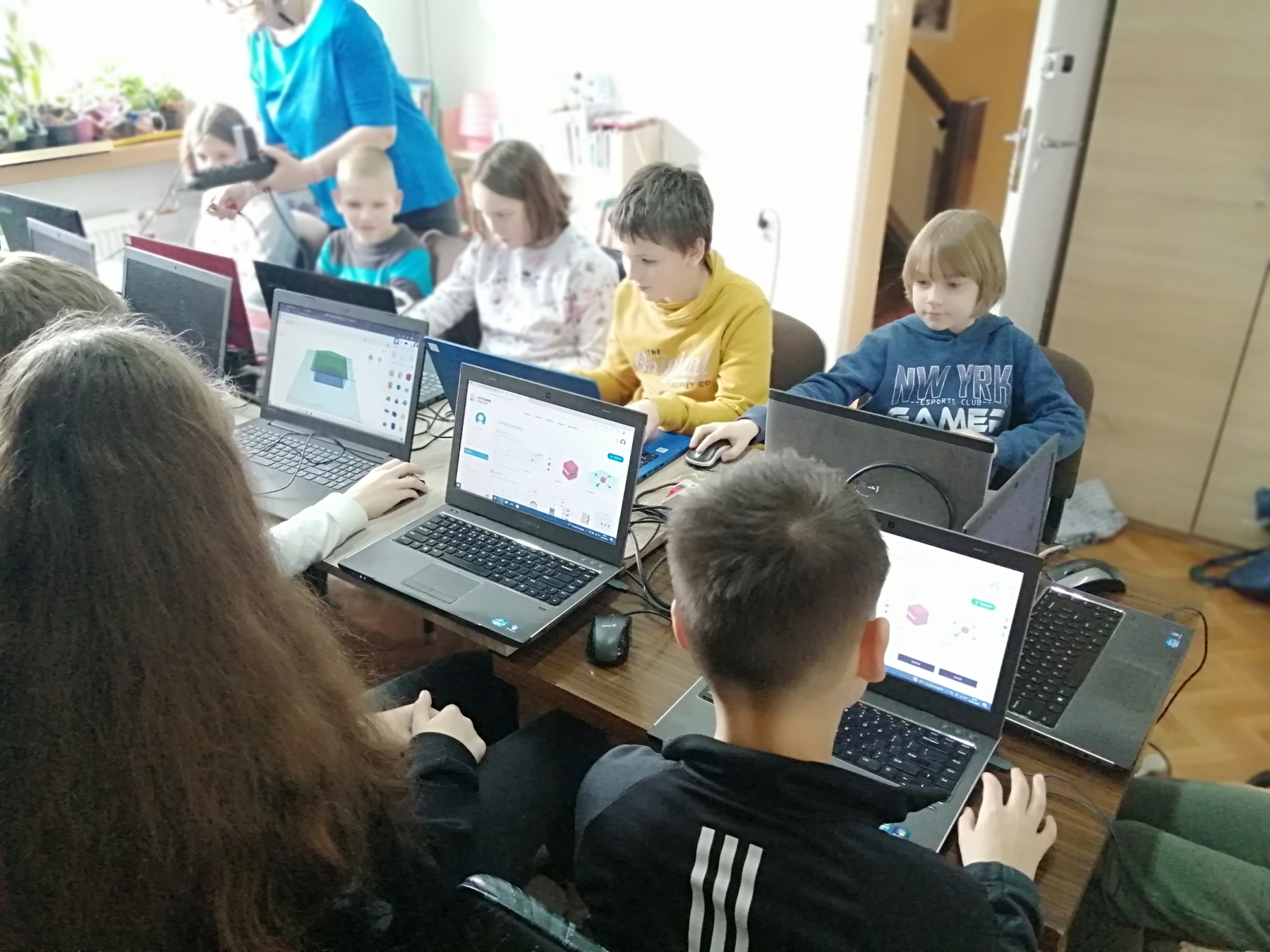 Młodzież przy laptopach projektuje breloczki 3D