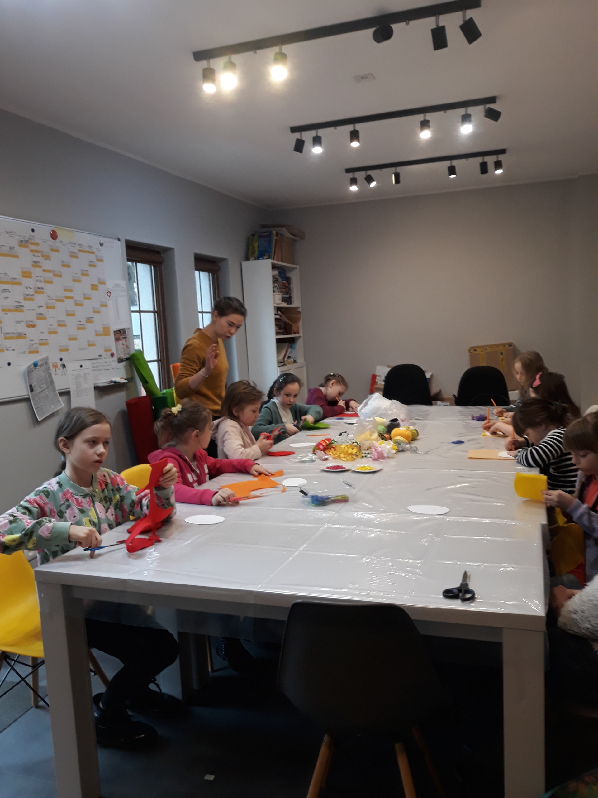 Dzieci siedzące przy stole i wycinające kształt pisanki z filcu