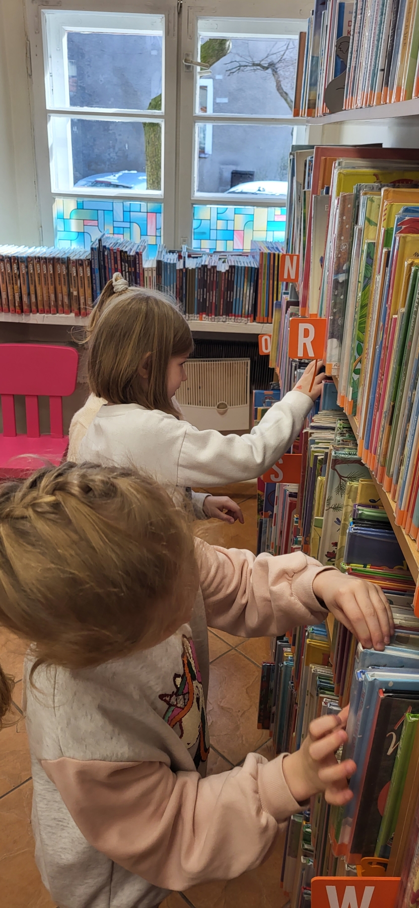 Dwójka dzieci przeglądająca książki na półkach