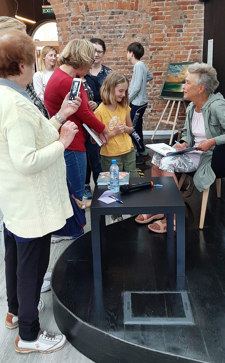 Dorota Sumińska rozmawiająca z publicznością i podpisująca książkę