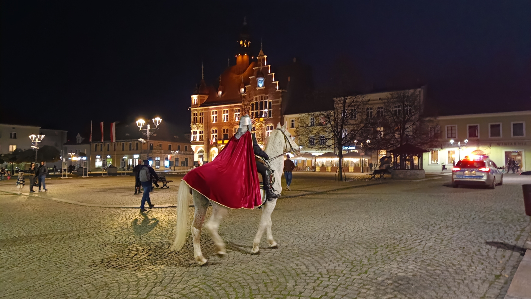 Aktorka przebrana za św. Marcina jedzie na koniu ulicą.