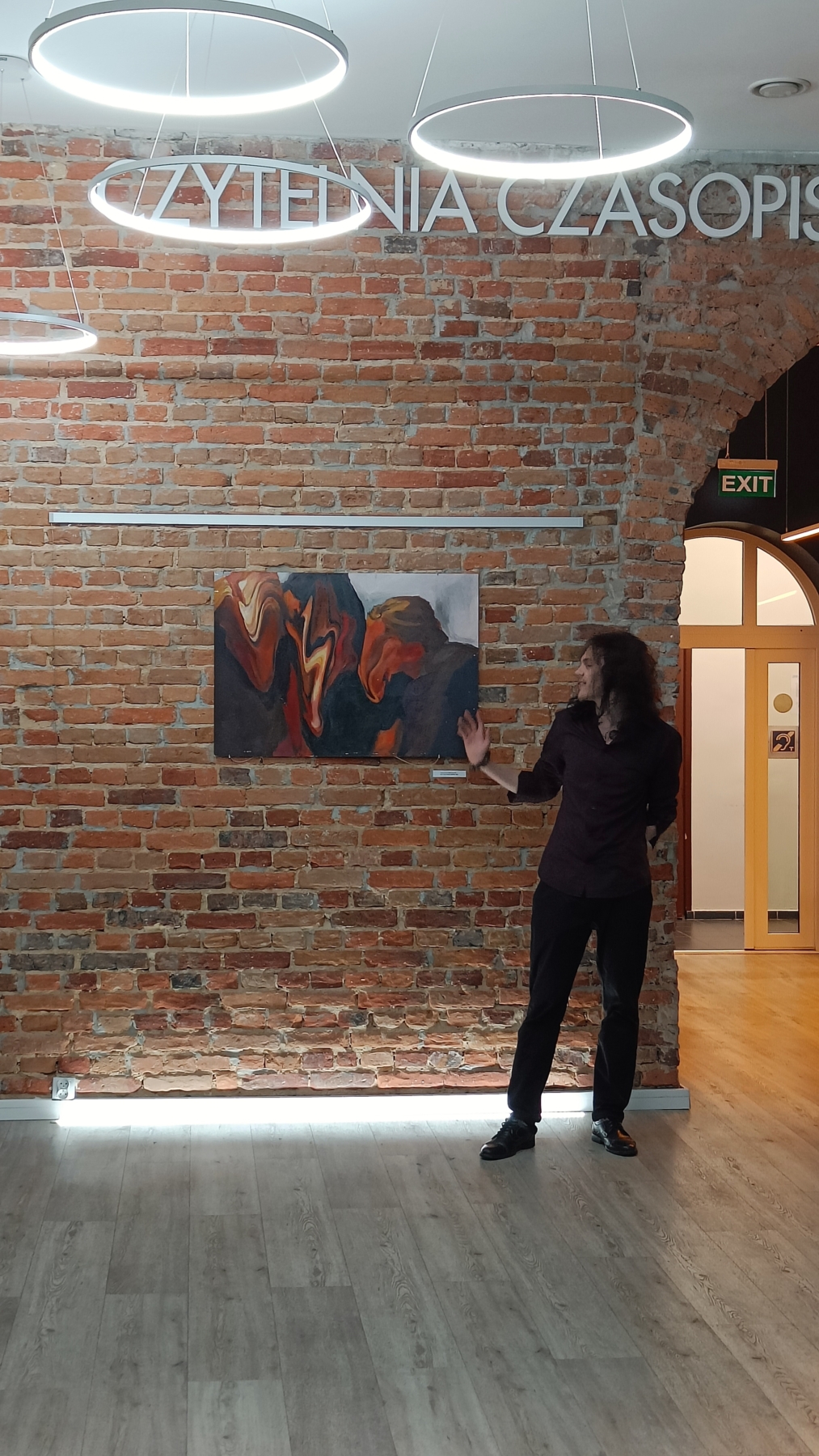 Michał Banaś pokazuje ręką swój obraz.