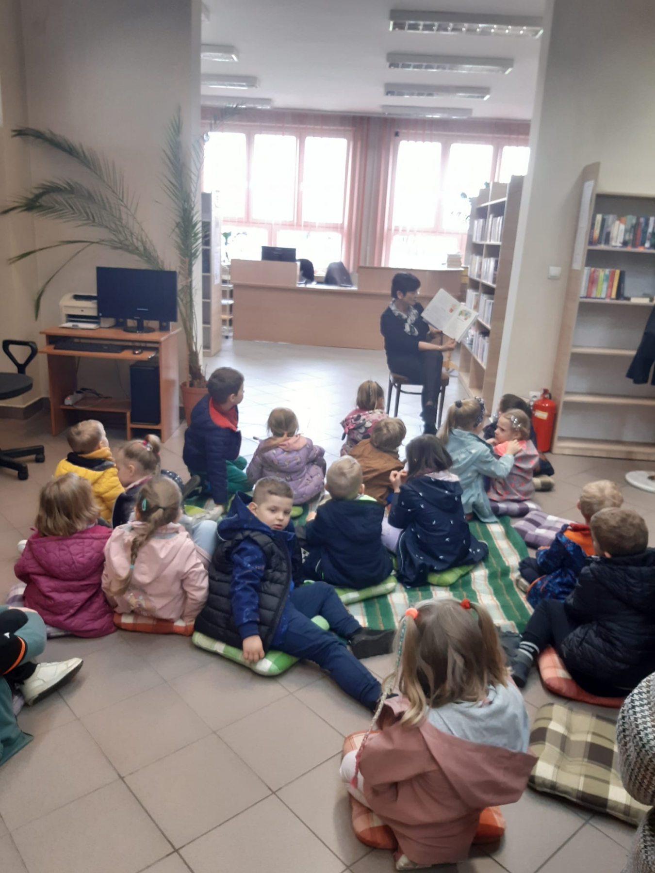 Dzieci słuchają bibliotekarki która pokazuje książkę